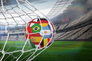 A ball made up of country flags is hitting the back of the net of a soccer goal.